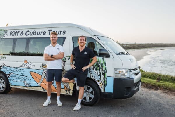 Kiff & Culture founders leaning on van with the coastline in the background